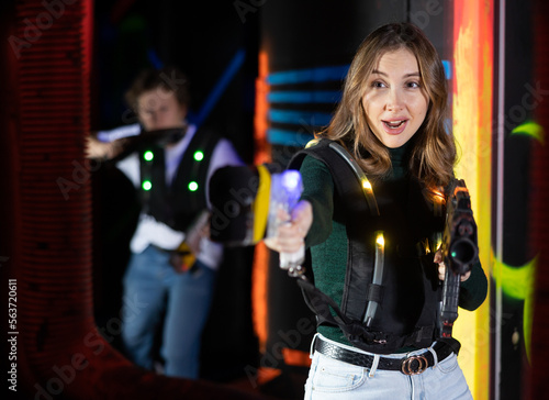 Smiling girl with laser pistol during playing laser tag with her friends in dark room © JackF