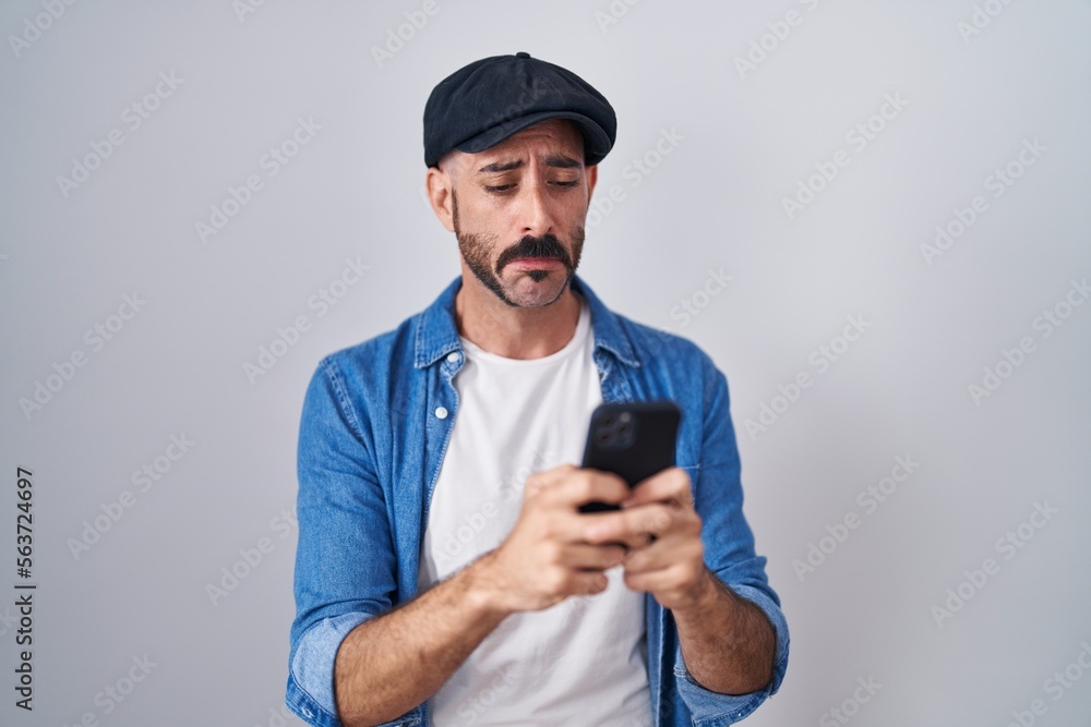 Hispanic man with beard using smartphone typing message depressed and worry for distress, crying angry and afraid. sad expression. Hispanic man with beard using smartphone typing message depressed and worry for distress, crying angry and afraid. sad expression.