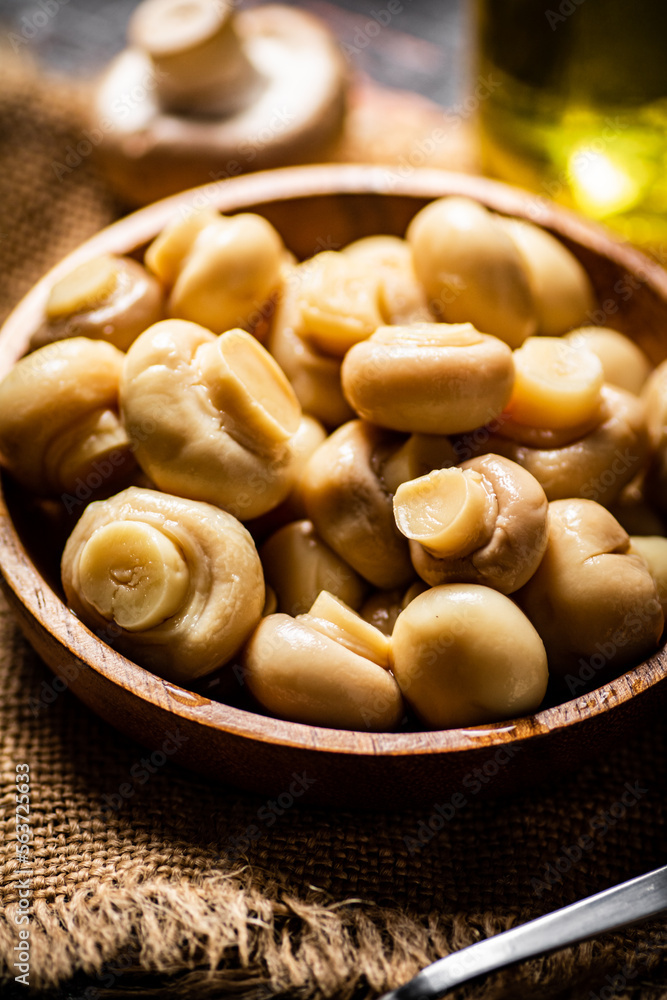 Wooden plate on burlap with pickled mushrooms. Wooden plate on burlap with pickled mushrooms.