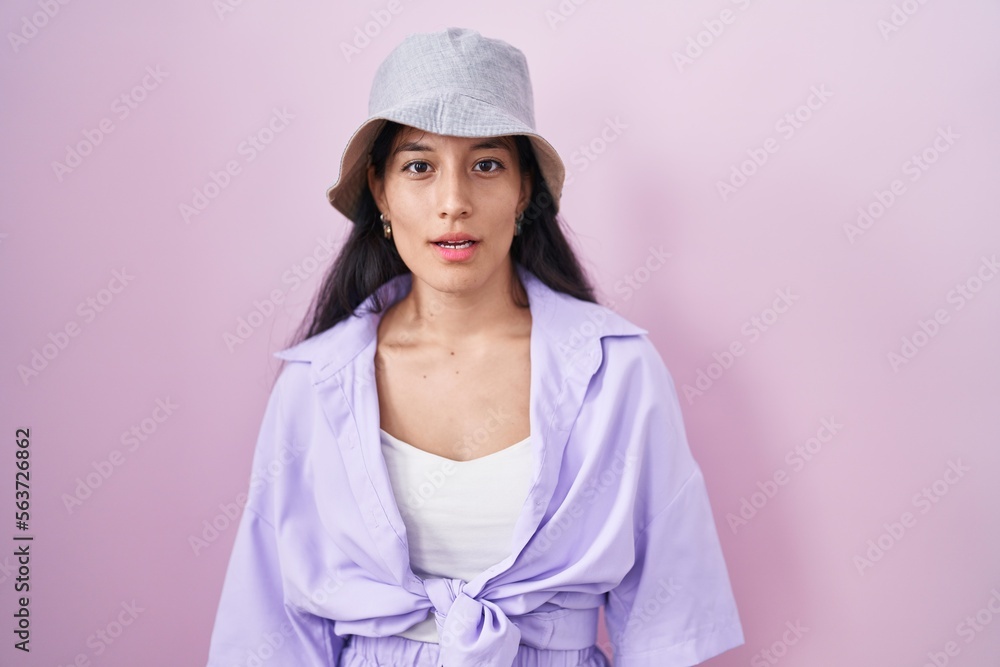 Young hispanic woman standing over pink background wearing hat looking sleepy and tired, exhausted for fatigue and hangover, lazy eyes in the morning. Young hispanic woman standing over pink background wearing hat looking sleepy and tired, exhausted for fatigue and hangover, lazy eyes in the morning.