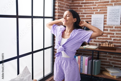 Young beautiful hispanic woman waking up stretching arms at home