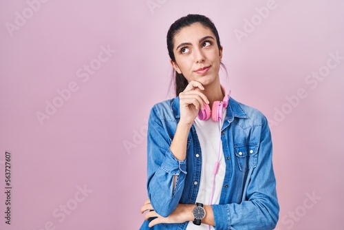 Young beautiful woman standing over pink background with hand on chin thinking about question, pensive expression. smiling with thoughtful face. doubt concept.