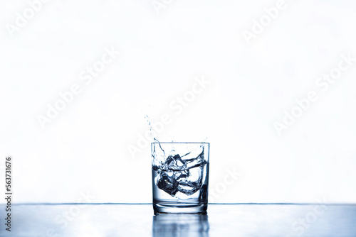 ice cubes splashing into glass water