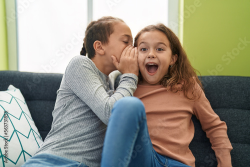 Two kids telling secret sitting on sofa at home © Krakenimages.com