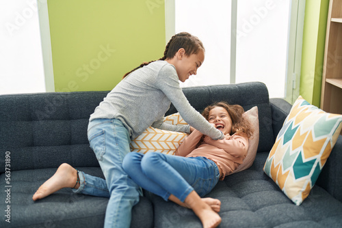 Two kids laughing for tickles sitting on sofa at home © Krakenimages.com