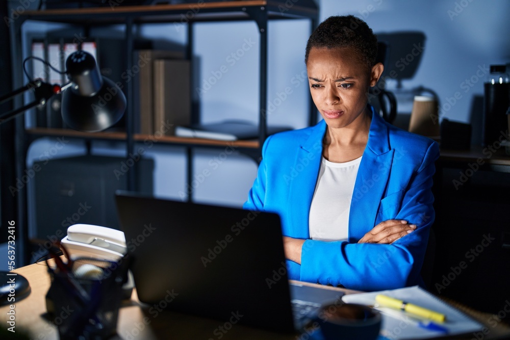 Beautiful african american woman working at the office at night skeptic and nervous, disapproving expression on face with crossed arms. negative person.