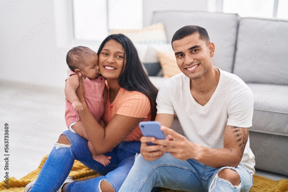 Hispanic family using smartphone sitting on floor at home Hispanic family using smartphone sitting on floor at home
