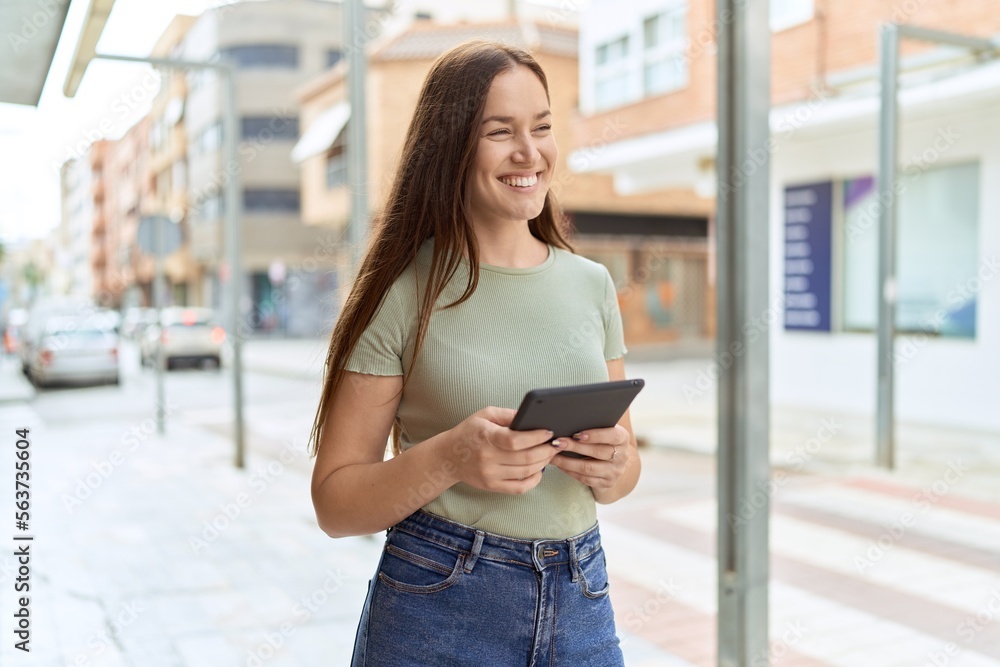Young beautiful woman smiling confident using touchpad at street