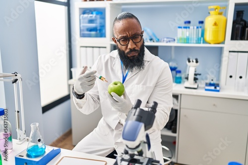 African american man working at scientist laboratory with apple depressed and worry for distress  crying angry and afraid. sad expression.