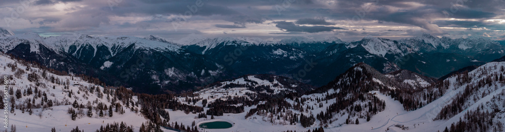Aerial drone panorama of Zoncolan ski resort in northern Italy on a cloudy winter day. Visible mountains around, good visibility.