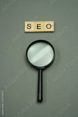 SEO written in wooden letters and magnifying glass.