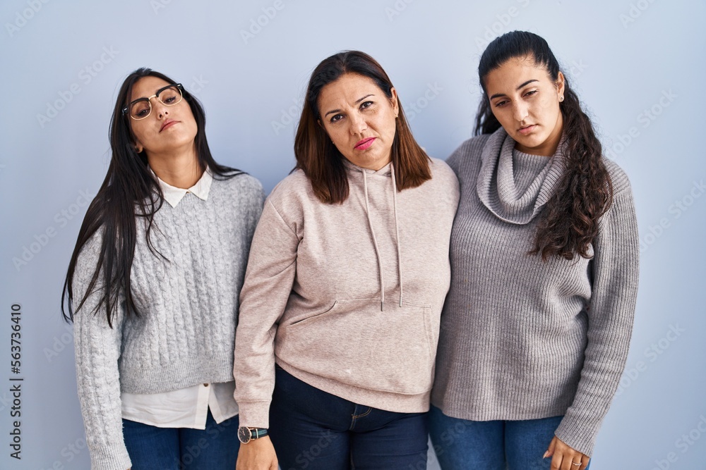 Mother and two daughters standing over blue background looking sleepy and tired, exhausted for fatigue and hangover, lazy eyes in the morning. Mother and two daughters standing over blue background looking sleepy and tired, exhausted for fatigue and hangover, lazy eyes in the morning.