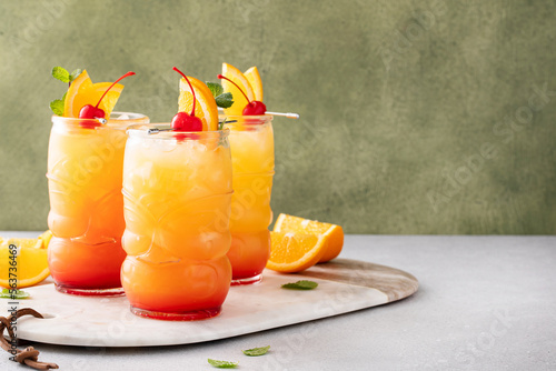 Rum punch in tiki glasses with orange slices and a cherry