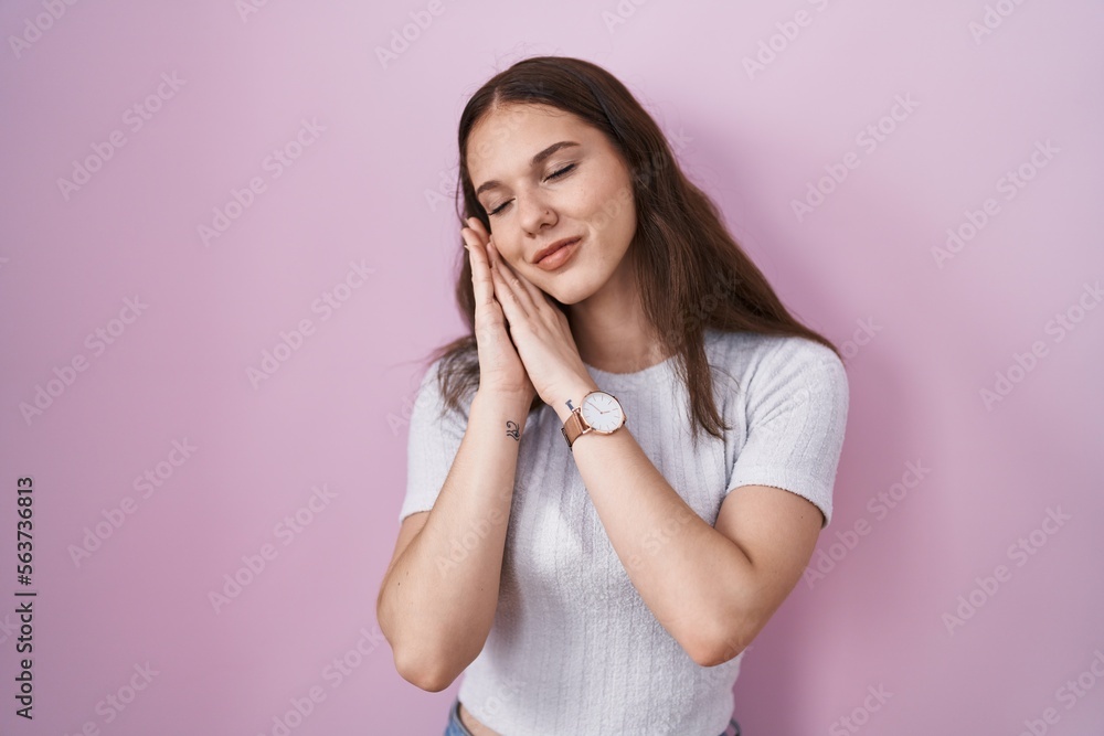 Young hispanic girl standing over pink background sleeping tired dreaming and posing with hands together while smiling with closed eyes. Young hispanic girl standing over pink background sleeping tired dreaming and posing with hands together while smiling with closed eyes.