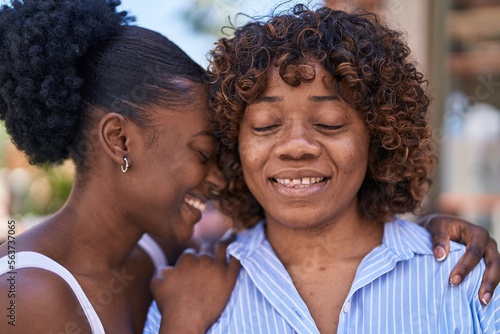 African american women mother and daughter hugging each other at street
