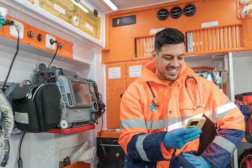 smiling paramedic using a cell phone inside an ambulance