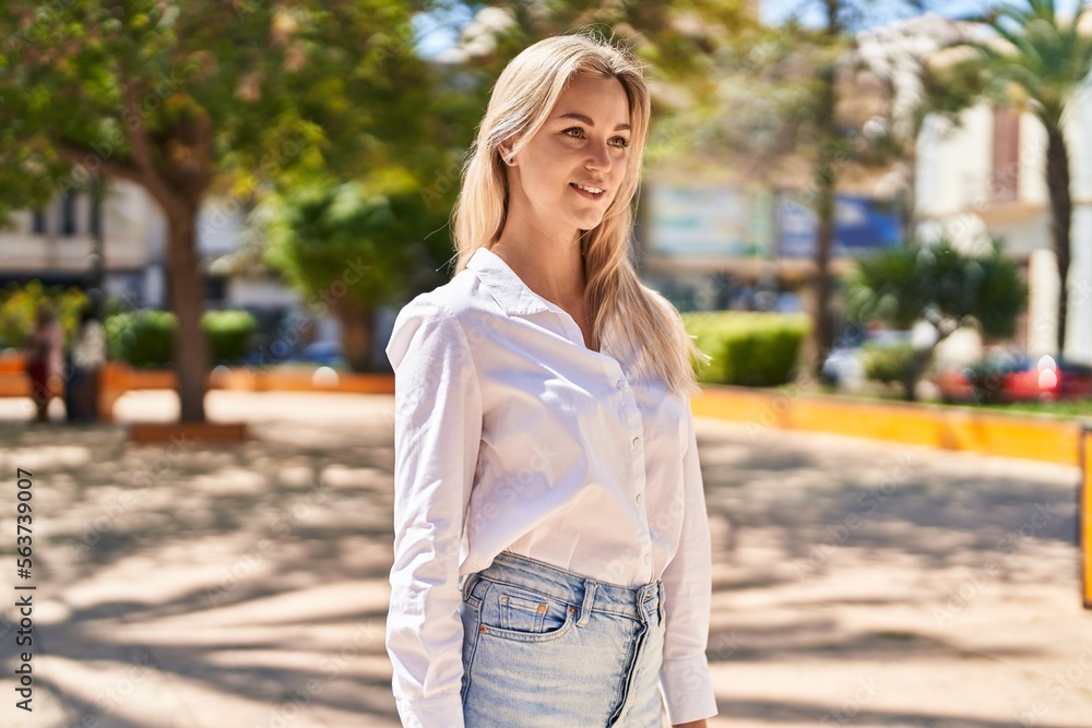Young blonde woman smiling confident standing at park