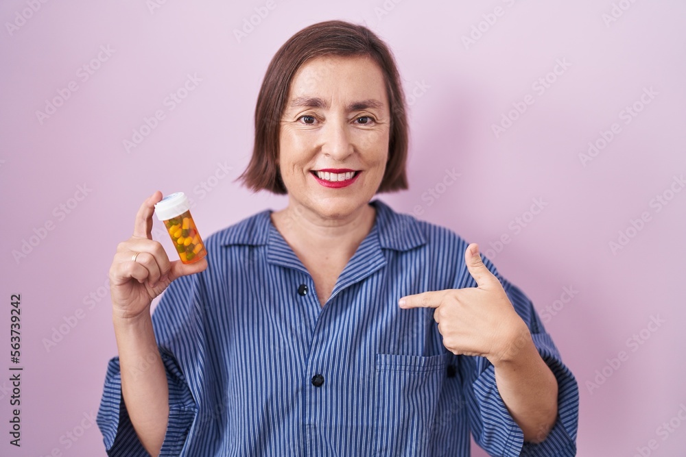 Middle age hispanic woman holding pills pointing finger to one self smiling happy and proud Middle age hispanic woman holding pills pointing finger to one self smiling happy and proud