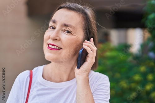 Middle age woman smiling confident talking on the smartphone at street