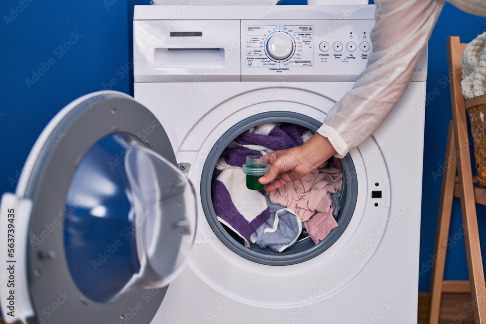 Middle age woman pouring detergent on washing machine at laundry room Middle age woman pouring detergent on washing machine at laundry room