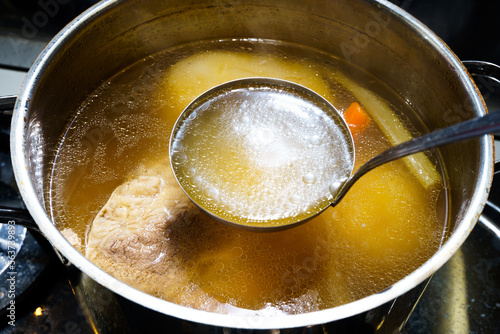 pot with ladle full of meat broth photo