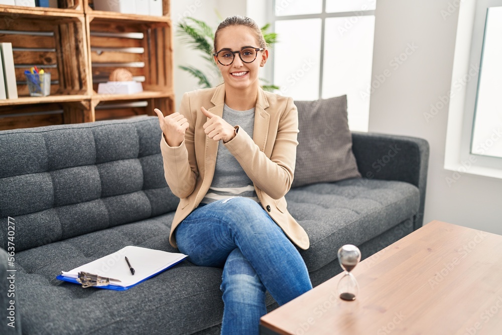 Young woman working at consultation office pointing to the back behind with hand and thumbs up, smiling confident Young woman working at consultation office pointing to the back behind with hand and thumbs up, smiling confident