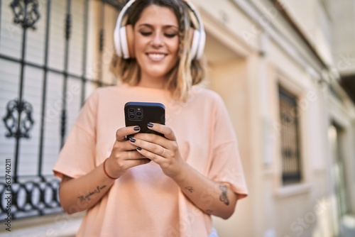 Young hispanic woman smiling confident listening to music at street