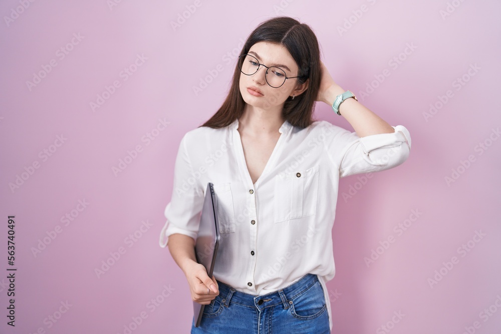 Young caucasian woman holding laptop confuse and wondering about question. uncertain with doubt, thinking with hand on head. pensive concept. Young caucasian woman holding laptop confuse and wondering about question. uncertain with doubt, thinking with hand on head. pensive concept.