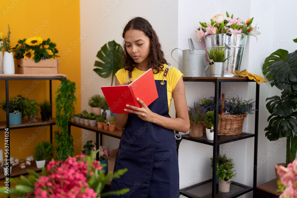 Young african american woman florist writing on notebook standing at flower shop Young african american woman florist writing on notebook standing at flower shop