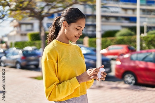 Young african american woman holding earphones at street