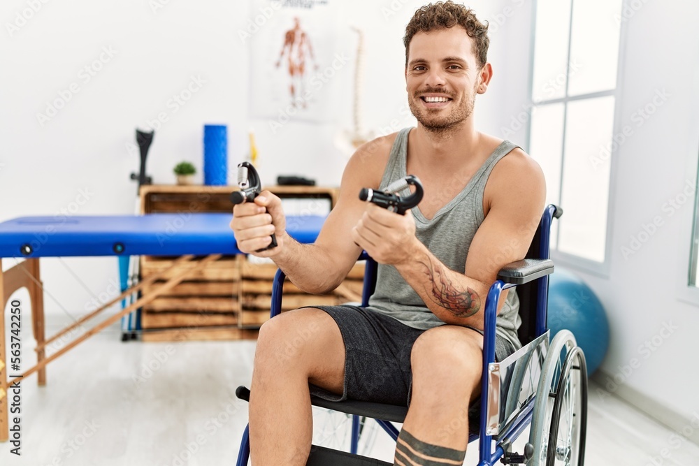 Young hispanic man doing rehab using hand grip sitting on wheelchair at clinic Young hispanic man doing rehab using hand grip sitting on wheelchair at clinic