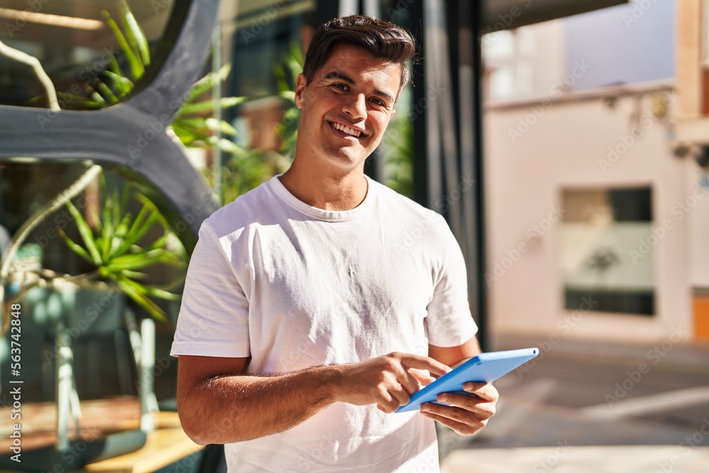 Young hispanic man smiling confident using touchpad at street Young hispanic man smiling confident using touchpad at street
