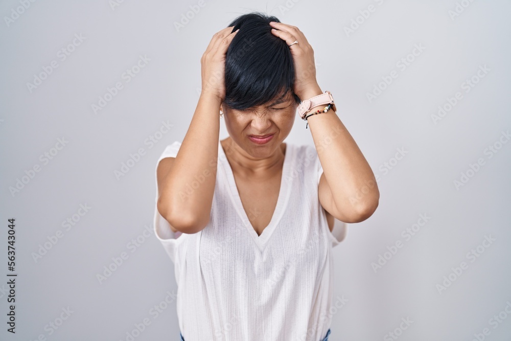 Young asian woman with short hair standing over isolated background suffering from headache desperate and stressed because pain and migraine. hands on head. Young asian woman with short hair standing over isolated background suffering from headache desperate and stressed because pain and migraine. hands on head.