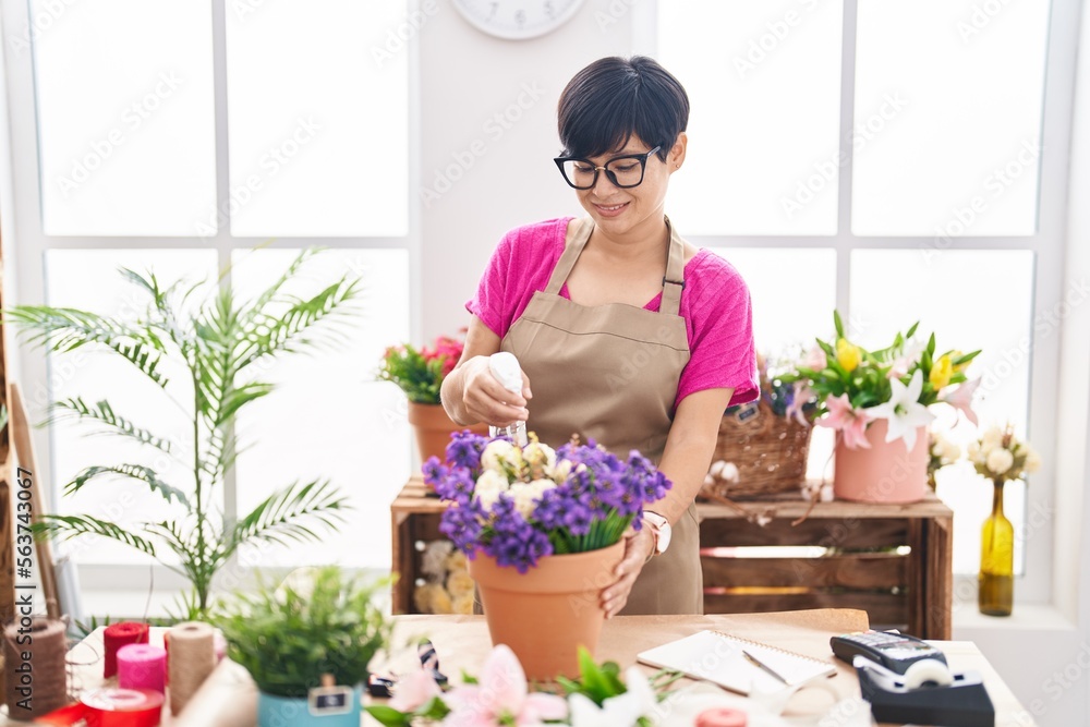 Middle age chinese woman florist using diffuser working at flower shop