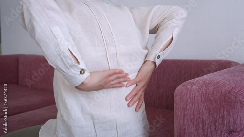Lady feel lumbago on couch. A view of woman holding his back after a lumbago attack on the couch.