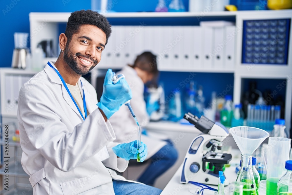 Man and woman scientists pouring liquid on test tube at laboratory Man and woman scientists pouring liquid on test tube at laboratory