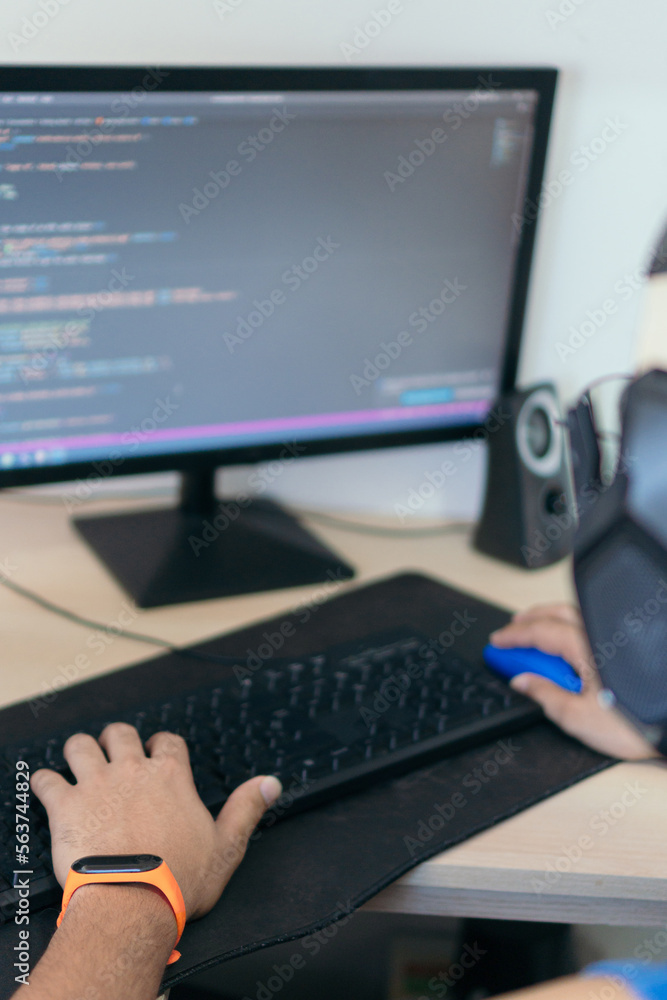 Naklejka premium Unrecognizable man sitting at table at home working remotely on computer