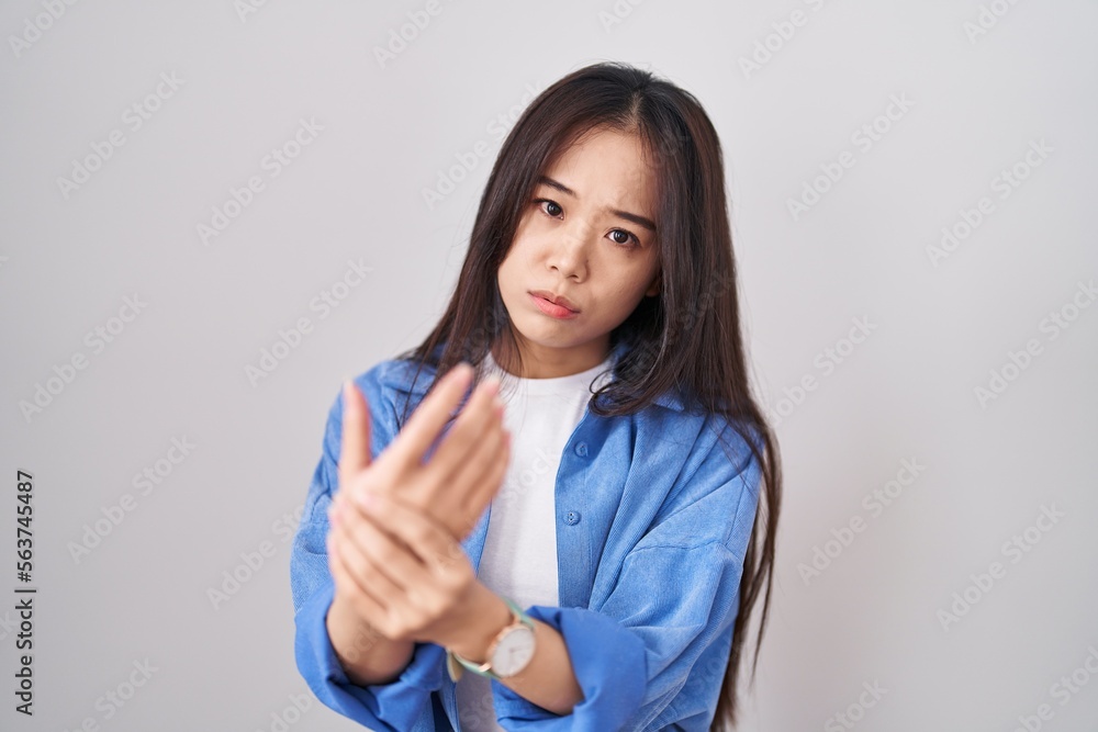 Young chinese woman standing over white background suffering pain on hands and fingers, arthritis inflammation Young chinese woman standing over white background suffering pain on hands and fingers, arthritis inflammation