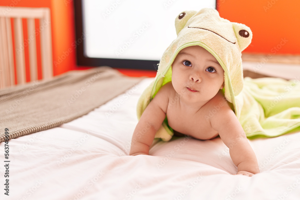 Adorable hispanic toddler wearing funny towel lying on bed at bedroom Adorable hispanic toddler wearing funny towel lying on bed at bedroom