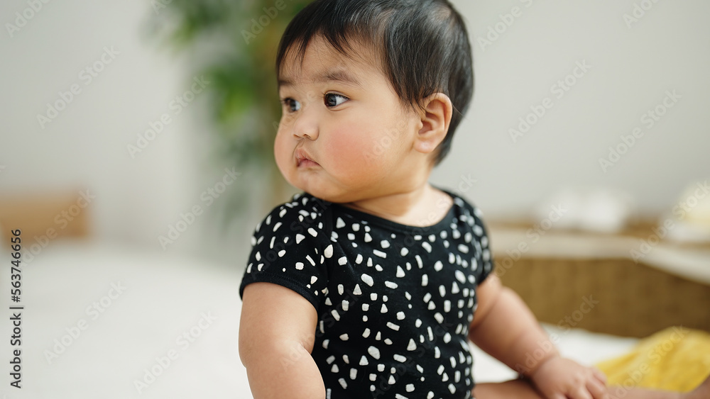 Adorable hispanic baby sitting on bed at home Adorable hispanic baby sitting on bed at home