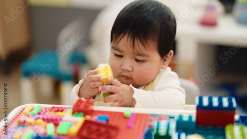 Adorable hispanic baby playing with construction blocks sitting on table at kindergarten © Krakenimages.com