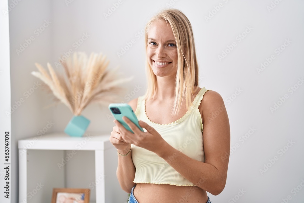 Young blonde woman smiling confident using smartphone at home Young blonde woman smiling confident using smartphone at home