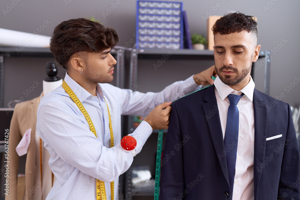 Two hispanic men tailor measuring sleeve jacket client at atelier Two hispanic men tailor measuring sleeve jacket client at atelier