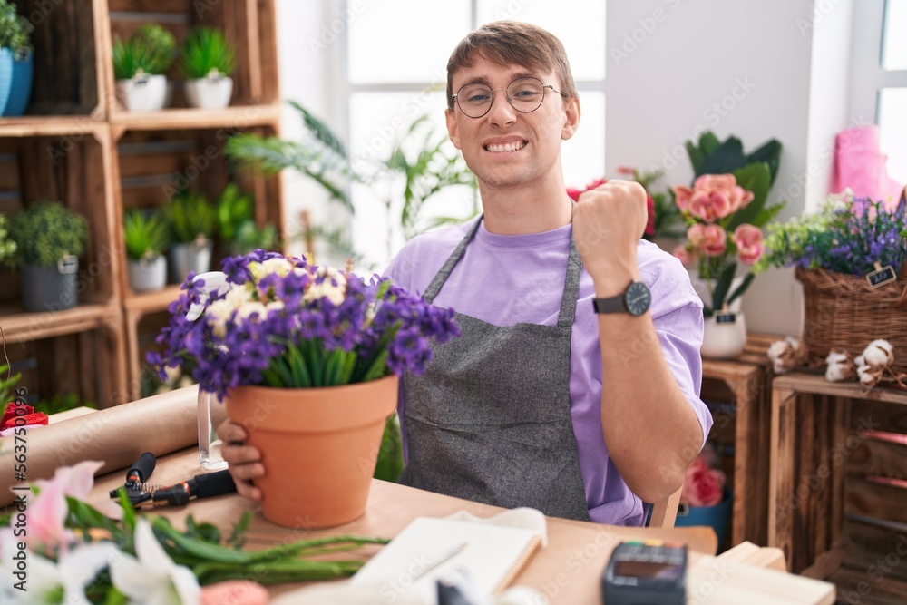 Caucasian blond man working at florist shop very happy and excited doing winner gesture with arms raised, smiling and screaming for success. celebration concept.
