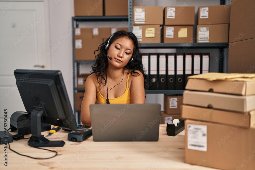 Young asian woman working at small business ecommerce wearing headset with serious expression on face. simple and natural looking at the camera. Young asian woman working at small business ecommerce wearing headset with serious expression on face. simple and natural looking at the camera.