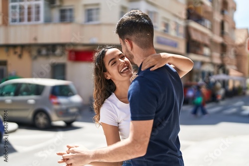 Young hispanic couple smiling confident hugging each other and dancing at street