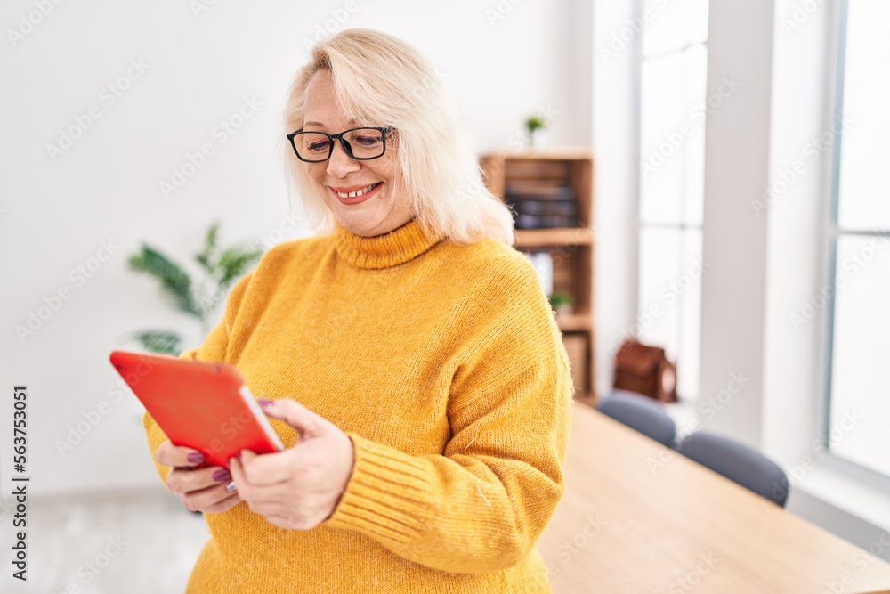 Middle age blonde woman business worker using touchpad at office Middle age blonde woman business worker using touchpad at office