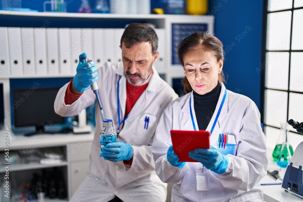 Middle age man and woman scientists working at laboratory Middle age man and woman scientists working at laboratory