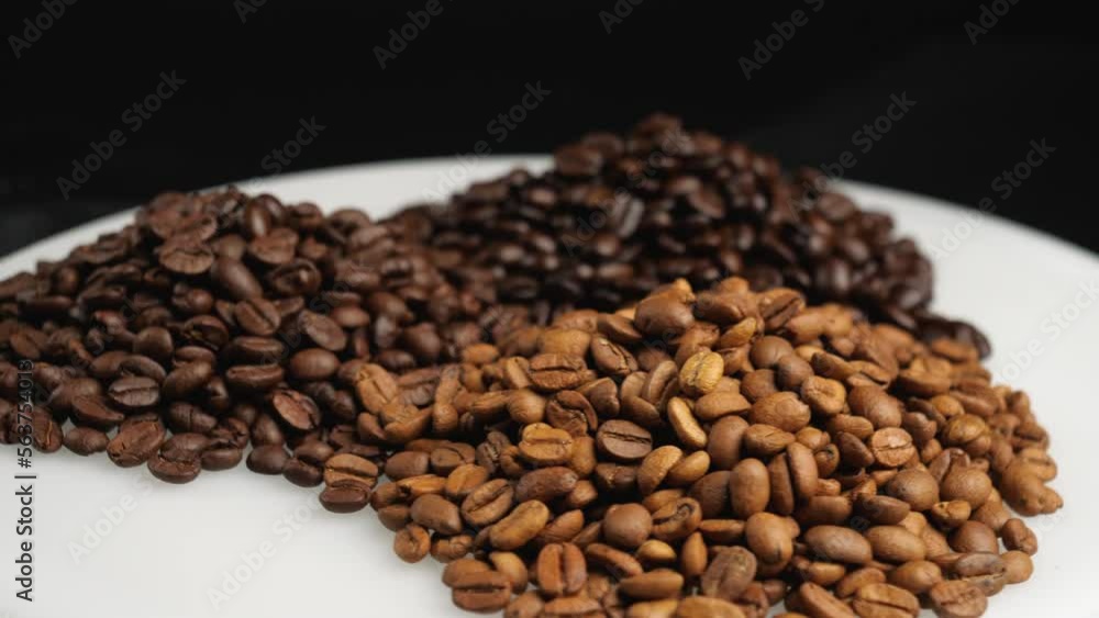 Roasted coffee beans, light roast, medium roast, dark roast pile on rotating table. Grain coffee, rotating video Roasted coffee beans, light roast, medium roast, dark roast pile on rotating table. Grain coffee, rotating video