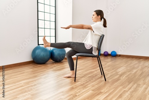 Young hispanic woman stretching at sport center.